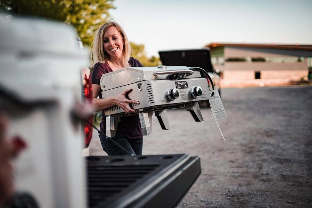 Woman Carrying Grill To Pickup Truck