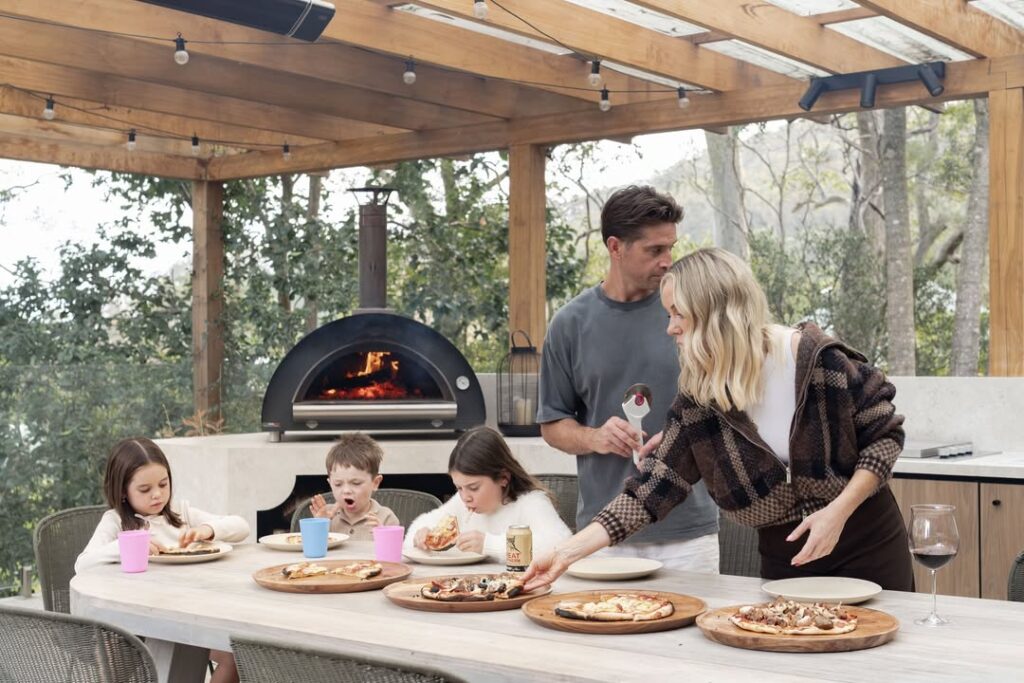 How To Grill Pizza Like A Pro 1 Family Enjoying Pizza On An Outdoor Kitchen