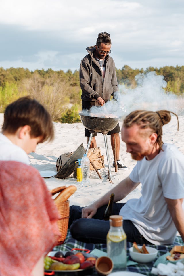 Sizzle By The Shore: How To Throw A Beach Bbq Party Everyone Will Love 1 Friends Grilling Drinking And Eating At A Perfect Spot At The Beach