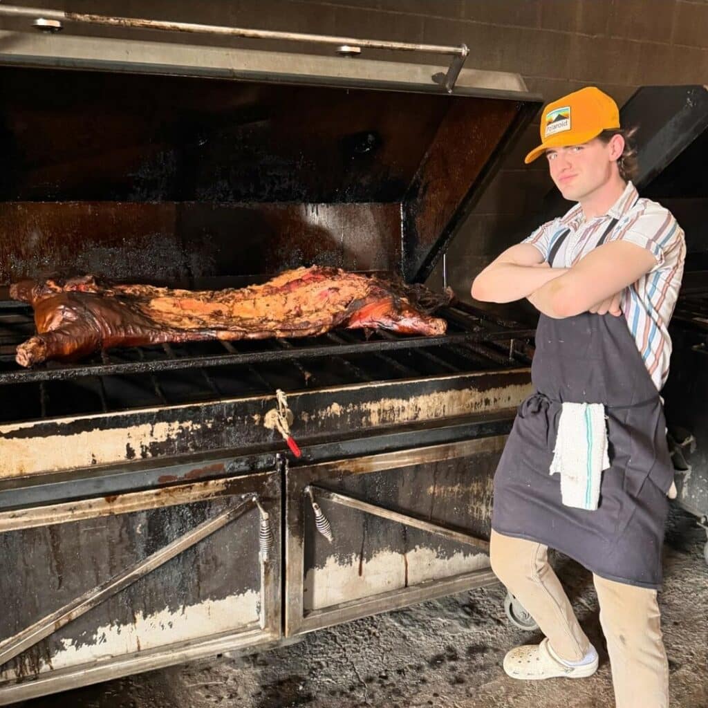 A Pitmaster Standing By The Grill With A Whole Hog