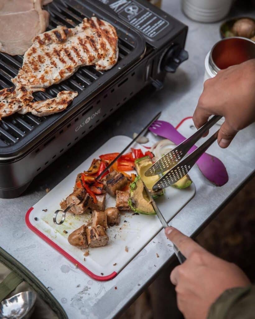 A Camper Prepping Food For The Gas One Grill