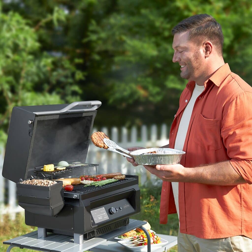 Man Smiles As He Cooks Food In An Electric Griddle