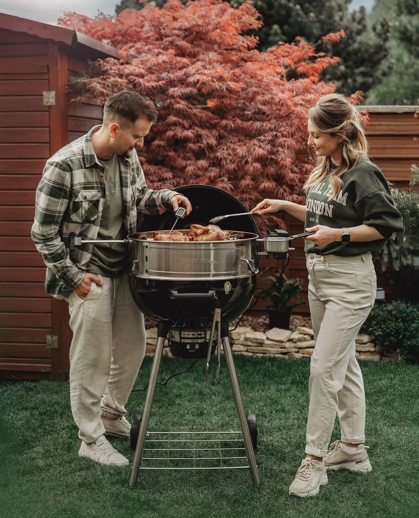 A Couple Grilling On A Charcoal Grill