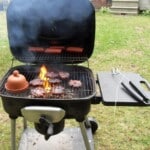 Burgers And Hot Dogs Cooking Over Flames On A Barbecue Grill