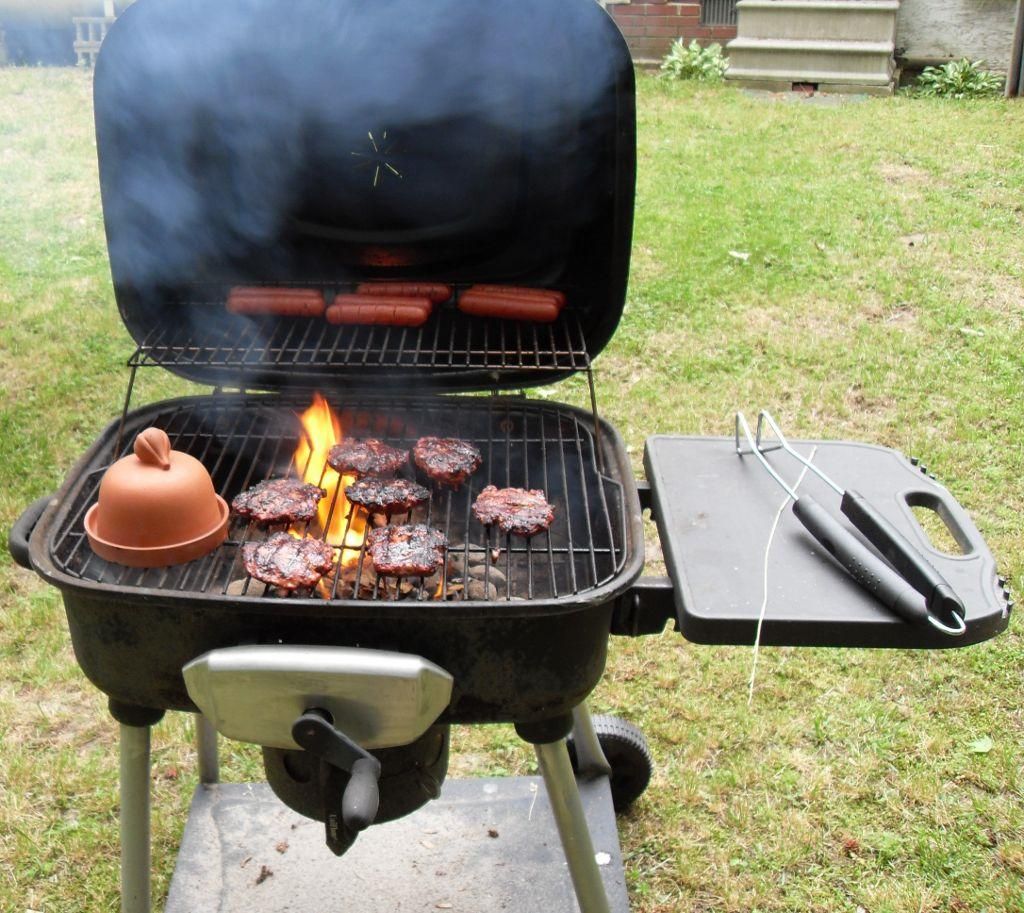 Burgers And Hot Dogs Cooking Over Flames On A Barbecue Grill