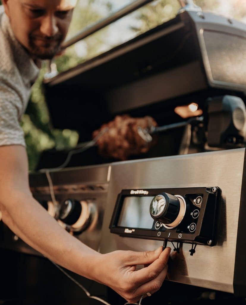 Man Adjusts Knobs And Digital Display Of The Broil King Gas Grill
