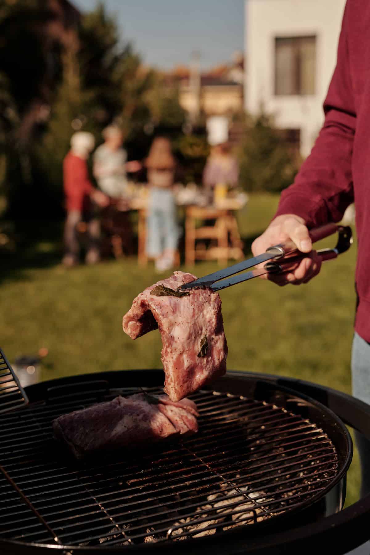 Person Grilling Steak At A Sunny Backyard Barbecue