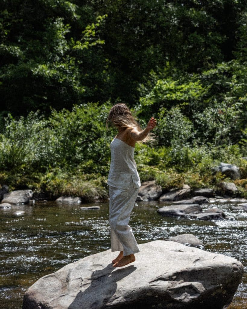 Woman Standing On A Boulder In The River